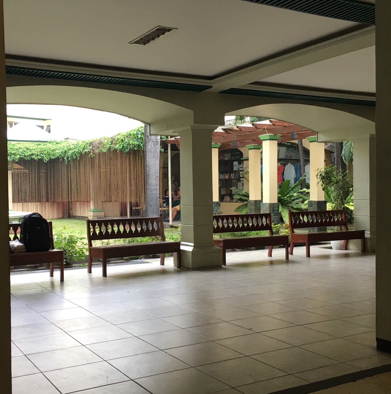 A shaded walkway with wooden benches beside the courtyard garden.